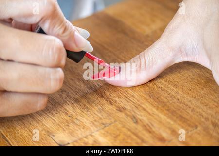 Frau, die ihren großen Finger mit einem halbpermanenten nagellack bemalt. Stockfoto