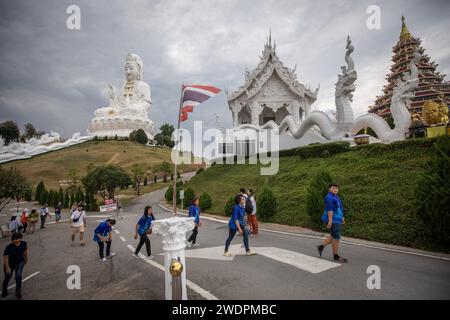 Chiang Rai, Thailand. Januar 2024. Thai-Einheimische gehen mit der Guanyin-Statue im Hintergrund. Der „Wat Huay Pla Kang“, auch bekannt als „großer Buddha von Chiang Rai“, ist bekannt für seine riesige weiße Statue von Guanyin (in der chinesischen Mythologie die Göttin der Barmherzigkeit). Der kürzlich erbaute Tempel ist eine Mischung aus thailändischem Lanna und chinesischem Stil und liegt auf einem Hügel im ländlichen Gebiet nördlich der Stadt Chiang Rai. Quelle: SOPA Images Limited/Alamy Live News Stockfoto