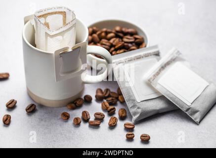 Eine Tasse frisch gebrühten Tropfkaffee. Tropfkaffee-Beutel mit gemahlenem Kaffee zum Brühen in einer Tasse Stockfoto