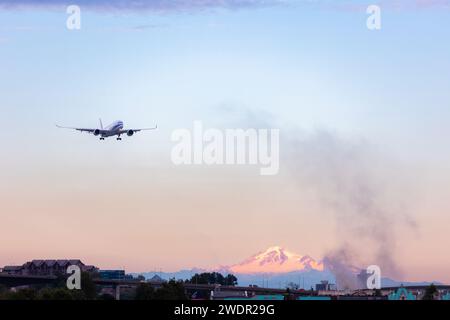 VANCOUVER, BC, KANADA - 27. JULI 2023: Boeing 777 mit Feuer in der Nähe von YVR in Richmond, BC, mit Mount Baker im Hintergrund, schwarzer Rauch, schwelend Stockfoto