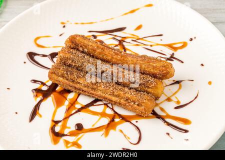 Heiße Churros mit Schokoladensauce auf Holztisch. Stockfoto