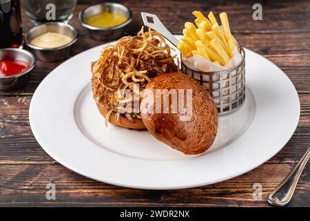 Veganer Burger mit knusprigen Zwiebeln, Saucen und Pommes Frites Stockfoto