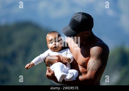 Nahaufnahme Porträt eines afro-amerikanischen Vaters, der ein multirassisches Baby küsst. Vater umarmt ein birassisches Kind draußen. Vater mit birassischem Baby über die Natur Stockfoto