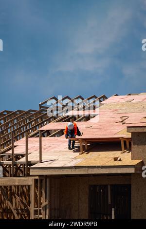 Dachüberdachung auf dem Dach. Dachbauer installieren neues Dach. Bauarbeiter, die eine große Dachwohnung überdacht haben. Zimmermann Stockfoto