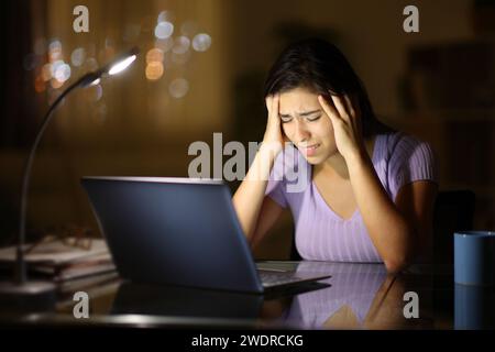 Besorgte Frau mit Laptop in der Nacht zu Hause Stockfoto