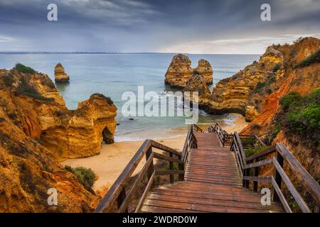 Algarve Küste in Lagos, Portugal, Praia do Camilo mit Holztreppen zum Strand am Atlantischen Ozean. Stockfoto