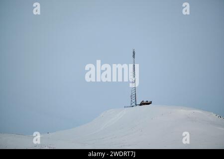 Antennenmast auf verschneiten Berggipfeln im Winter Stockfoto