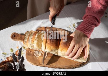 Eine Frau, die Brot aus Hanfsamen auf einem Holzbrett schneidet. Stockfoto