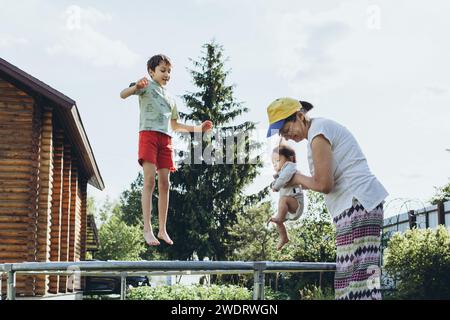 Oma mit Enkeln, die auf einem Trampolin im Hof springen Stockfoto