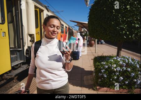 Kaukasische Touristen-Pendler am Bahnhof, mit Smartphone, Online-Karte, soziale Medien, mobile Anwendung, Hotelbuchung, Ticketkauf Stockfoto