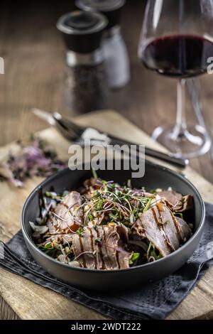 Roastbeef Salat mit Kräutern und Balsamico Soße im Stil einer Schüssel auf einem Restauranttisch. Stockfoto