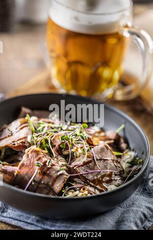 Roastbeef Salat mit Kräutern und Balsamico Soße im Stil einer Schüssel auf einem Restauranttisch. Stockfoto