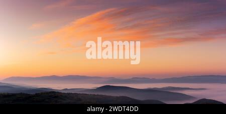 Panorama eines Himmels über den karpaten mit Nebel im Tal bei Sonnenaufgang. Wolken in roten und orangen Farben einer aufgehenden Sonne Stockfoto