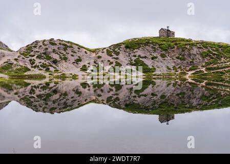 Die kleine Kirche und die Reflexion der alpinen Landschaft im ruhigen Wasser, OLBE Seen, Sappada, Karniche Alpen, Provinz Udine Stockfoto