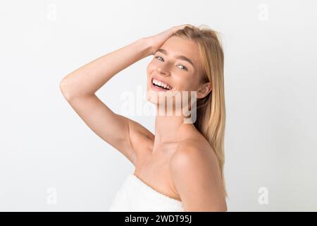Attraktive blonde junge Dame, die ihr Haar und ihren Kopf berührt, Studio Stockfoto