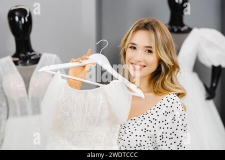 Junge, schöne Frau sucht sich ein Kleid für die Hochzeit in einem Hochzeitssalon aus. Stockfoto