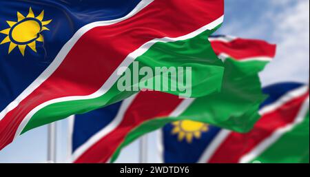 Namibische Nationalflaggen winken an einem klaren Tag. Blaue Streifen, gelbe Sonne, rote, weiße Streifen, grün. Ovambo-Farbe. 3D-Darstellung. Selektiver lichtwellenleiter Stockfoto