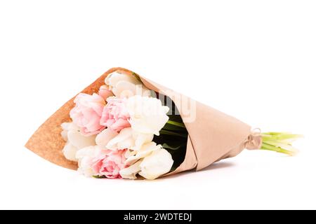 Ein Bündel weißer und rosafarbener Doppeltulpen, die in recyceltem braunem Papier verpackt sind, isoliert auf weißem Hintergrund. Tulpenstrauß. Stockfoto