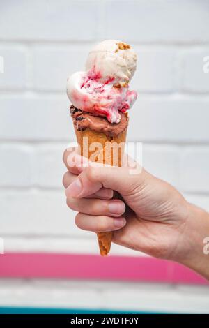 Eis Waffelkegel Eiscreme in der Hand mit weißem gemauertem Hintergrund. Stockfoto