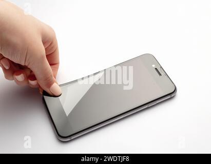 Trennen der Schutzscheibe vom Smartphone auf weißem Hintergrund. Stockfoto