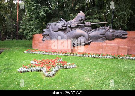 Links befindet sich der Teil der Gedenkstätte mit einem „Eid“-Thema, ein Soldat führt Pferde. Am Denkmal des Ruhms im Panfilov Park in Almaty, Kasachstan. Stockfoto