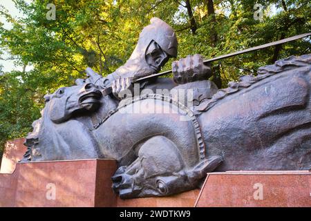 Links befindet sich der Teil der Gedenkstätte mit einem „Eid“-Thema, ein Soldat führt Pferde. Am Denkmal des Ruhms im Panfilov Park in Almaty, Kasachstan. Stockfoto