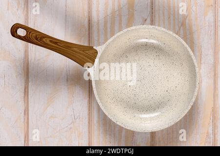 Runde Bratpfanne auf einem verwitterten Hintergrund aus weißem Holz. Antihaftbeschichtete, keramikbeschichtete Kochtechnologie. Stockfoto