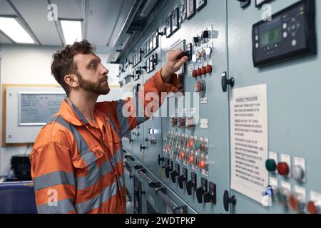 Junger Marineingenieur, der die Arbeit an elektrischen Anlagen in der Maschinenschaltwarte überwacht. Stockfoto