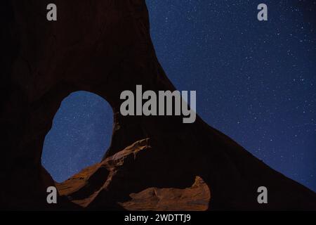 Sterne und Mondlicht durch den Ear of the Wind Arch bei Nacht im Monument Valley Navajo Tribal Park in Arizona. Stockfoto