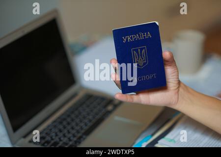 Ukrainischer Pass in der Hand in der Nähe des Computers. Hochwertige Fotos Stockfoto