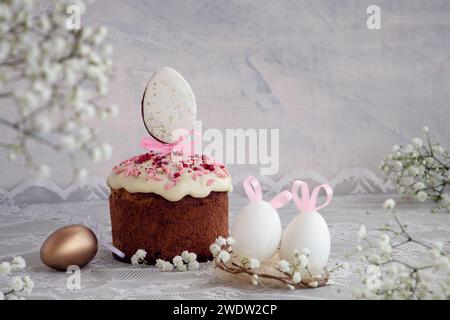 Happy Easter-Konzept. Osterlichttafel mit Osterkuchen und farbigen Eiern und Hasenohren. Weiße Frühlingsblumen. Weichzeichner. Kopierbereich, Stockfoto
