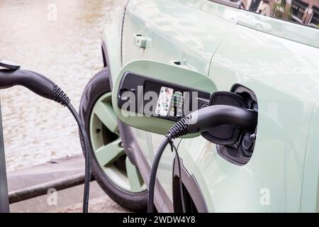 Ladeanschluss eines elektrischen Plug-in-Hybrid Land Rover Defender, der an einer öffentlichen Ladestation in Amsterdam, Holland, aufgeladen wird. Stockfoto