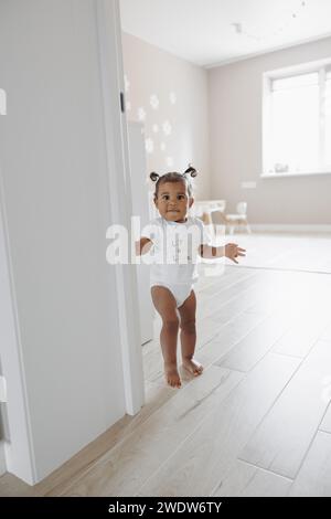 Gemischtes Kleinkind, das im Zimmer läuft. Afrokaukasisches kleines Mädchen. Das Konzept der interrassischen Familie. Stockfoto