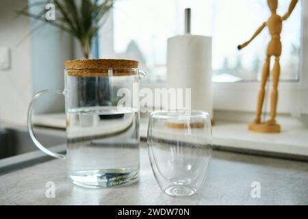 Kanne mit frischem Wasser und Glas auf dem Tisch in der Küche Stockfoto