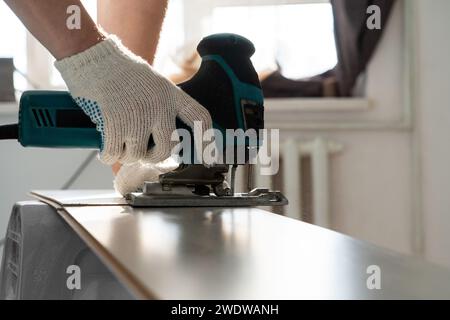 Man sägt Laminat. Der Mann repariert den Boden im Haus, Laminatboden im Stil alter Bretter. Stockfoto