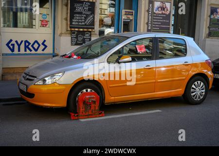 Auto mit einer Radklemme das rote Schloss wird auf ein Rad gelegt, um sicherzustellen, dass die Strafe durchgesetzt und die Geldstrafe bezahlt wird, besonders Stockfoto