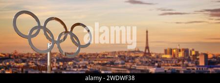 Olympische Ringe bei Sonnenuntergang mit dem Eiffelturm in Paris Frankreich Panoramahintergrund, Webbanner der olympischen Sommerspiele 2024 in Paris Stockfoto
