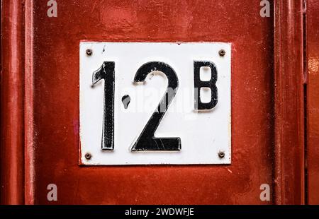 Adressschild an der Holztür des Wohngebäudes mit der Wohnungsnummer zwölf. Hausausweisschild Stockfoto
