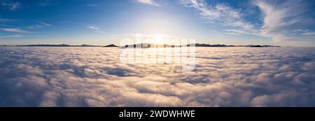 Landschaft über den Wolken mit Berggipfeln bei Sonnenaufgang. Dramatische Wolkenlandschaft aus der Vogelperspektive. Stockfoto