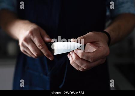 Die Hände des Mannes überprüfen das Küchenmesser, der Häuptling mit einem scharfen Messer Stockfoto