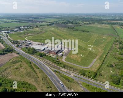 Luftbild des Flugplatzes Manchester Barton mit Hangars und Kontrollturm, Liverpool Road im Vordergrund und Felder in der Ferne Stockfoto