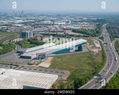 Luftaufnahme der Hallen-Skipiste von Chill Factore am Beyond, Autobahn M60 mit dem Trafford Centre & Manchester City Centre in der Ferne Stockfoto