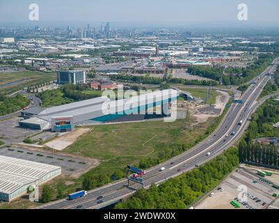 Luftaufnahme der Hallen-Skipiste von Chill Factore am Beyond, Autobahn M60 mit dem Trafford Centre & Manchester City Centre in der Ferne Stockfoto