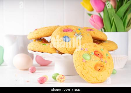 Bunte Funfetti-Schokoladenchips mischen Cookies. Hausgemachte süße Ostervanillenkekse mit Zuckerstreuseln und Ostereiern aus Schokolade, auf weißer Küche Stockfoto