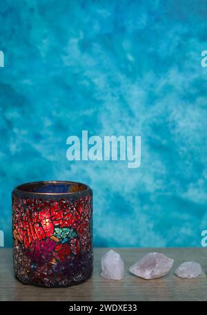 Farbenfroher Glaskerzenbehälter auf Holztisch vor blauem Hintergrund. Stockfoto