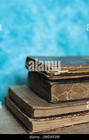 Stapel alter Bücher auf einem Holztisch mit blauem Hintergrund. Stockfoto