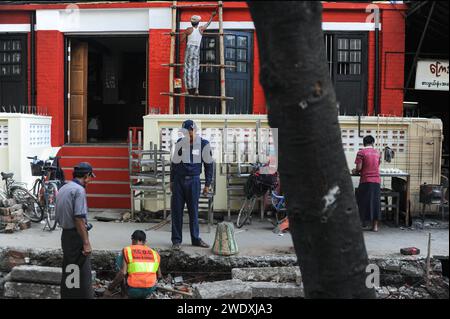 22.04.2014, Yangon, Myanmar, Asien - Arbeiter bei Bauarbeiten auf einer Strasse und an einem Gebaeude im Zentrum der ehemaligen Hauptstadt Rangun. *** 22 04 2014, Yangon, Myanmar, Asien Arbeiter, die Bauarbeiten an einer Straße und einem Gebäude im Zentrum der ehemaligen Hauptstadt Yangon durchführen Stockfoto