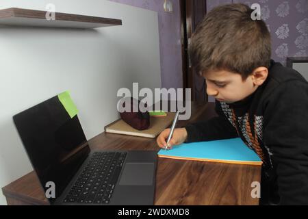 Online-Fernunterricht. Schuljunge studiert zu Hause und macht Hausaufgaben. Gelangweilter Student, der versucht, Komposition zu schreiben. Bleiben Sie zu Hause. Stockfoto
