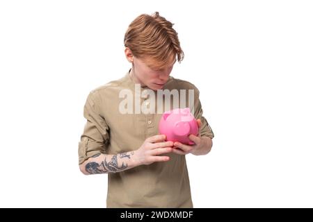 Junger gutaussehender rothaariger Student, der Sparkasse hält Stockfoto