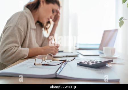 Brille und Taschenrechner Nahaufnahme und müde Buchhalterin, die Markierungen in Papierdokumenten mit modernem Laptop sitzendem Hintergrund am nächsten hellen Tag macht Stockfoto